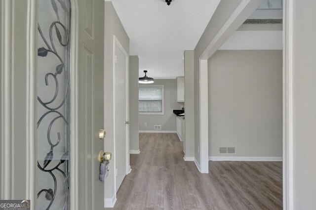 foyer featuring wood finished floors, baseboards, and visible vents