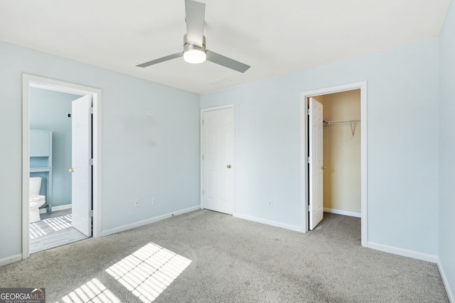 unfurnished bedroom featuring carpet floors, baseboards, ensuite bathroom, and a walk in closet