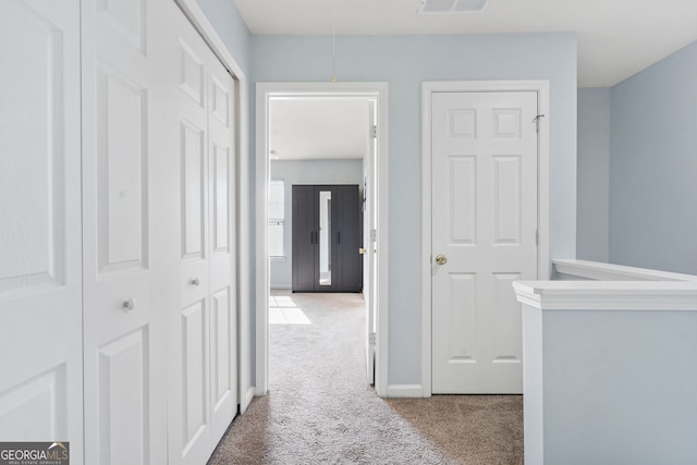 corridor with baseboards, carpet flooring, attic access, and visible vents