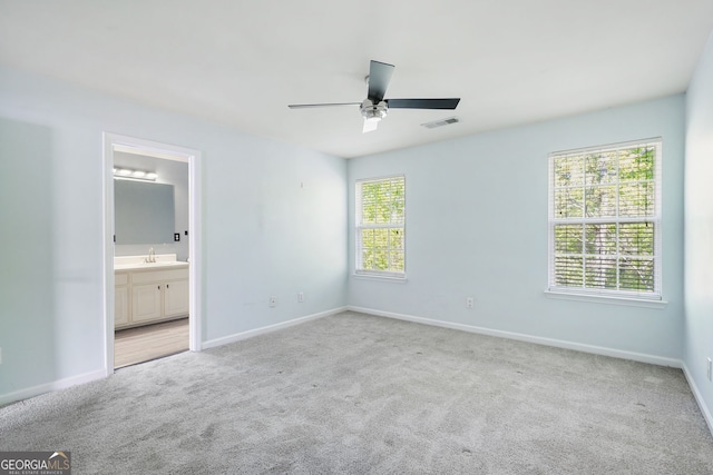 unfurnished bedroom with a sink, baseboards, carpet flooring, and visible vents