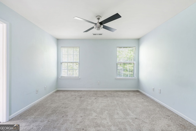 spare room with baseboards, a ceiling fan, carpet, and a wealth of natural light