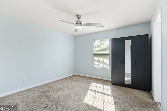 carpeted empty room with visible vents, a ceiling fan, and baseboards