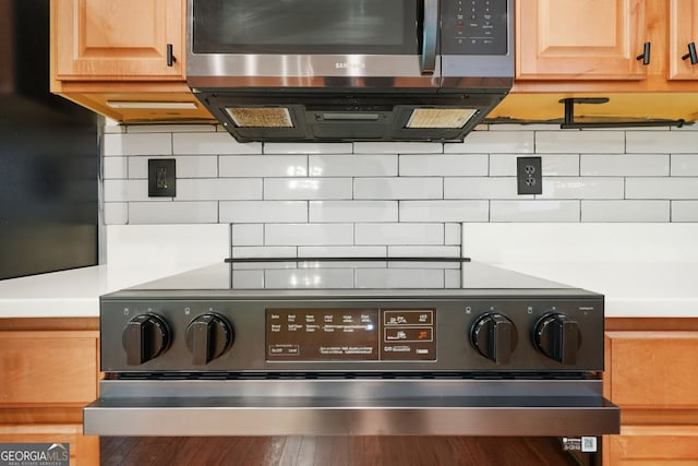 interior details featuring light countertops, stainless steel microwave, electric stove, and tasteful backsplash