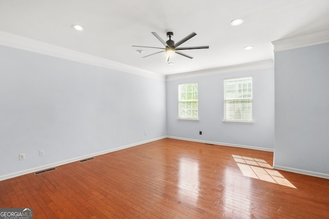 empty room with a ceiling fan, visible vents, crown molding, hardwood / wood-style flooring, and baseboards