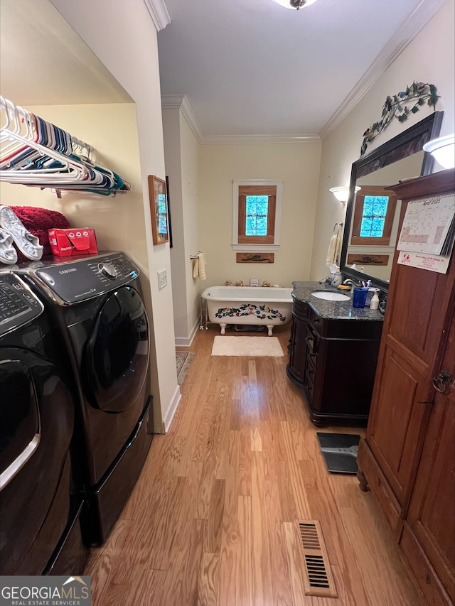 135 Southlake Dr, Moultrie, GA 31768 - laundry room featuring light wood-type flooring, ornamental molding, washing machine and dryer, and baseboards