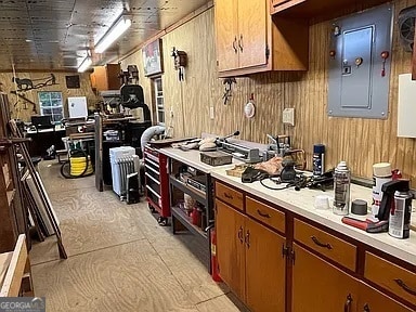 135 Southlake Dr, Moultrie, GA 31768 - kitchen with light countertops, electric panel, wood walls, and brown cabinetry
