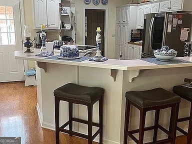 135 Southlake Dr, Moultrie, GA 31768 - kitchen with freestanding refrigerator, a kitchen breakfast bar, a peninsula, and white cabinetry