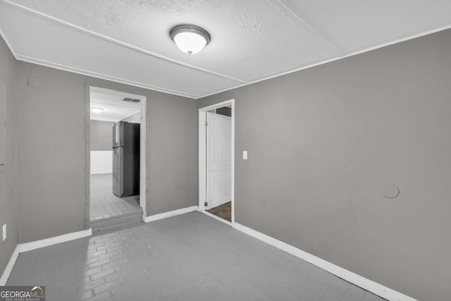 spare room with baseboards and a textured ceiling