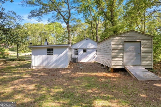 rear view of property with a storage shed, an outdoor structure, and central air condition unit