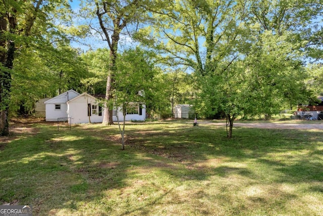 view of grassy yard featuring a storage unit and an outbuilding