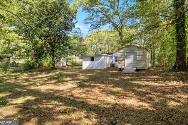 view of yard featuring a storage unit, an outbuilding, and fence