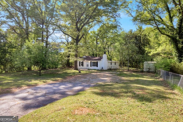 view of front of house featuring asphalt driveway, a chimney, and stucco siding