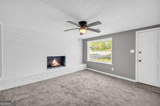 unfurnished living room with a textured ceiling, a ceiling fan, a brick fireplace, carpet floors, and baseboards