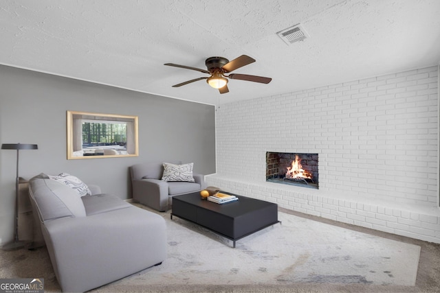 living area featuring a ceiling fan, a fireplace, a textured ceiling, carpet, and brick wall
