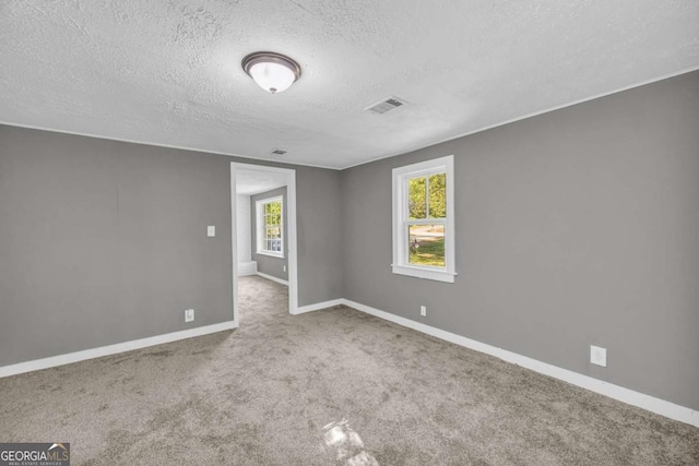 carpeted spare room featuring a textured ceiling and baseboards