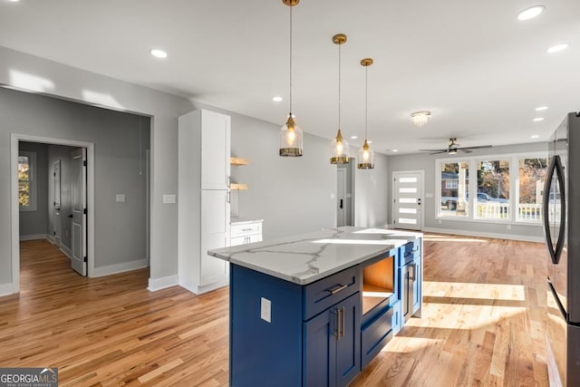 kitchen featuring baseboards, open shelves, freestanding refrigerator, light wood-type flooring, and blue cabinets