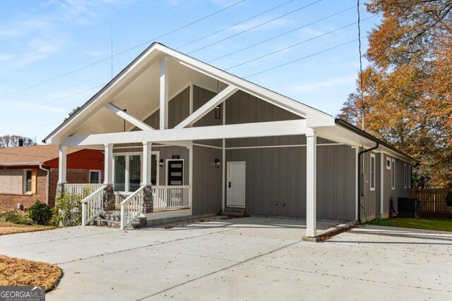 view of front of property featuring a carport, covered porch, central AC unit, and concrete driveway