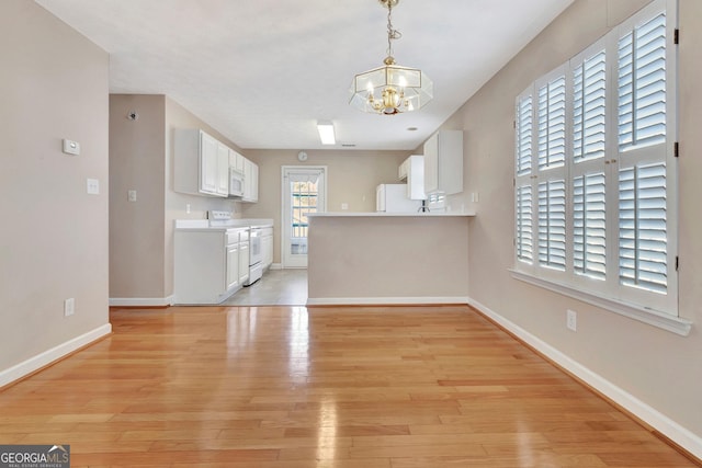 unfurnished living room with baseboards, light wood finished floors, and a chandelier