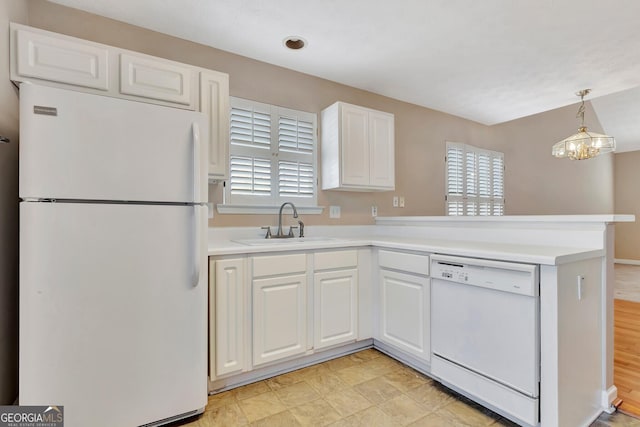 kitchen featuring a peninsula, a sink, white appliances, and a wealth of natural light