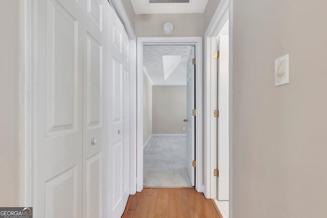 hall featuring light wood-style flooring and visible vents