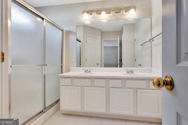 bathroom featuring tile patterned flooring, a sink, a stall shower, wallpapered walls, and double vanity