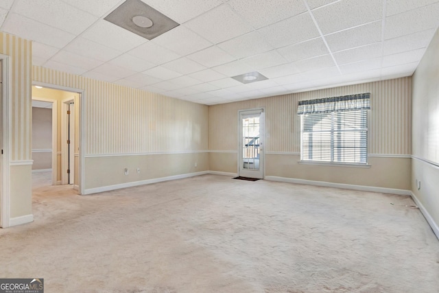 carpeted spare room with baseboards and a drop ceiling