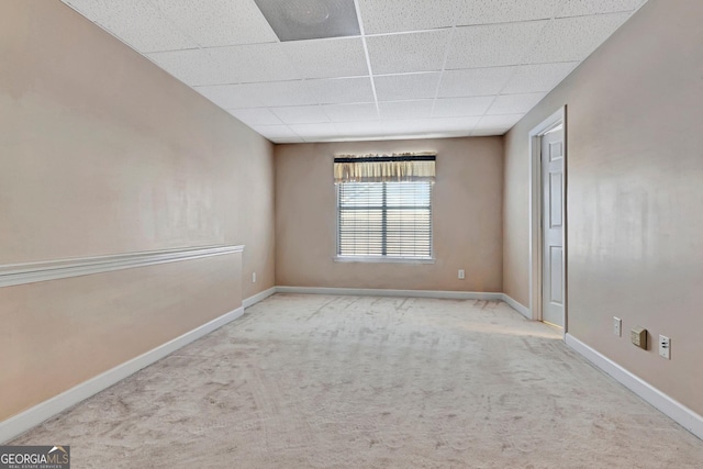 spare room featuring baseboards, a drop ceiling, and carpet