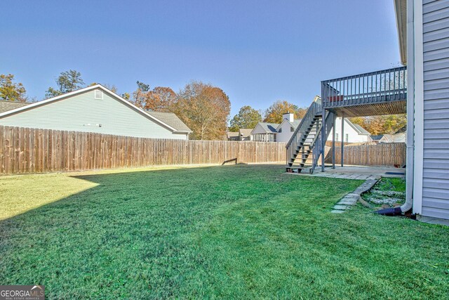view of yard with a patio, a fenced backyard, a wooden deck, and stairs