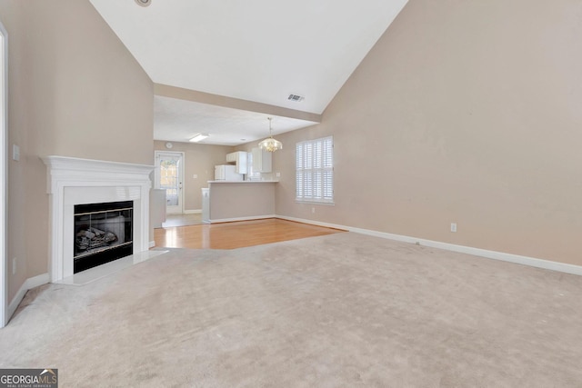 unfurnished living room with a notable chandelier, baseboards, carpet flooring, a fireplace with flush hearth, and visible vents