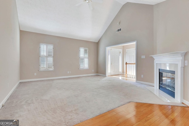 unfurnished living room featuring light carpet, high vaulted ceiling, baseboards, and a ceiling fan