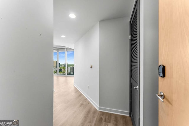 hallway with floor to ceiling windows, recessed lighting, baseboards, and wood finished floors