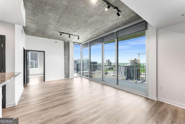 interior space with track lighting, light wood-style floors, expansive windows, and a view of city