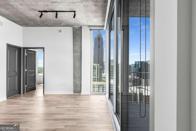 interior space with wood finished floors, baseboards, rail lighting, and floor to ceiling windows