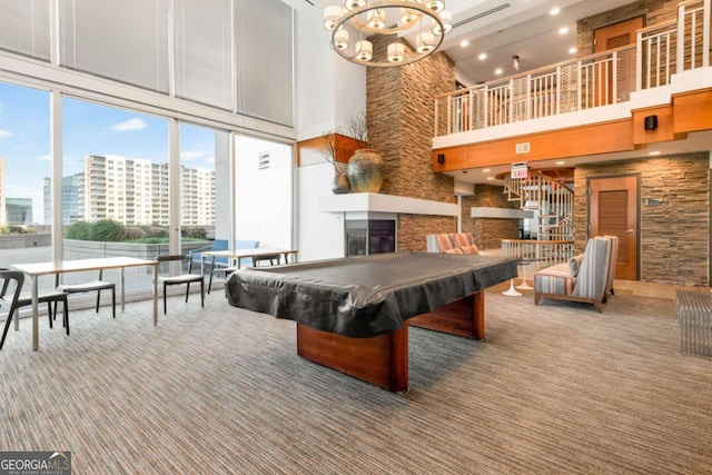 playroom with billiards, a glass covered fireplace, a chandelier, carpet, and a high ceiling