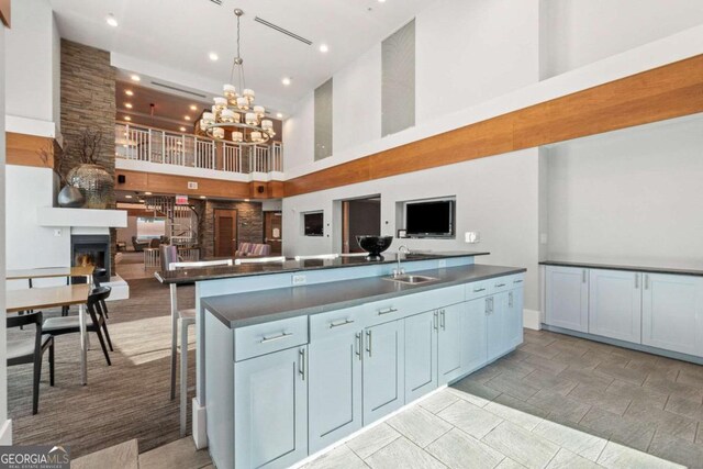 kitchen featuring open floor plan, a sink, a towering ceiling, and dark countertops