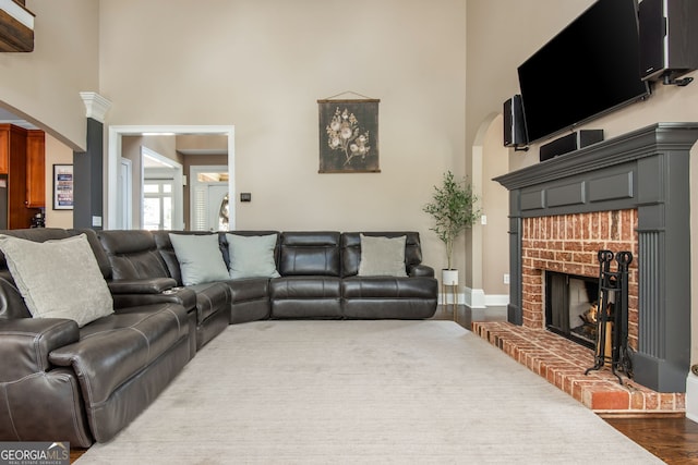 living area with dark wood finished floors, baseboards, a towering ceiling, and a fireplace