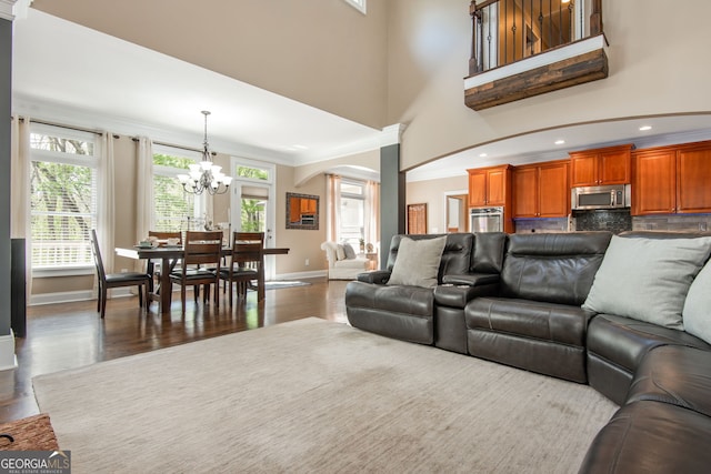 living room with a chandelier, arched walkways, wood finished floors, and baseboards