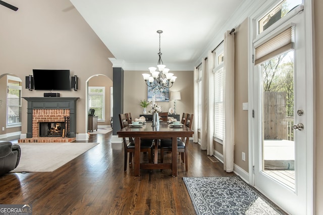 dining area with arched walkways, an inviting chandelier, dark wood finished floors, and plenty of natural light