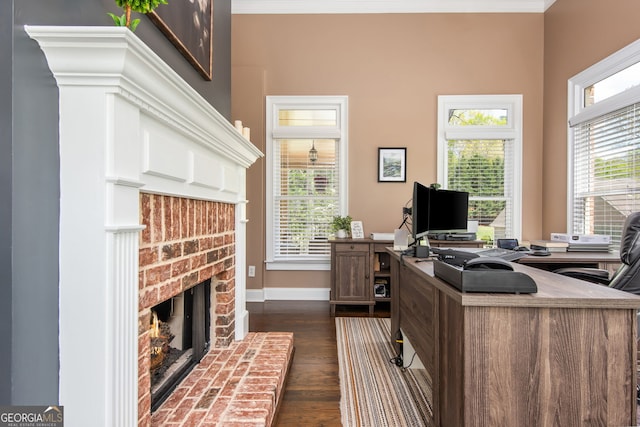 office featuring dark wood-style flooring, a brick fireplace, baseboards, and a healthy amount of sunlight