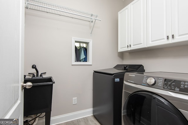 laundry area featuring cabinet space, baseboards, light wood-type flooring, and washing machine and dryer
