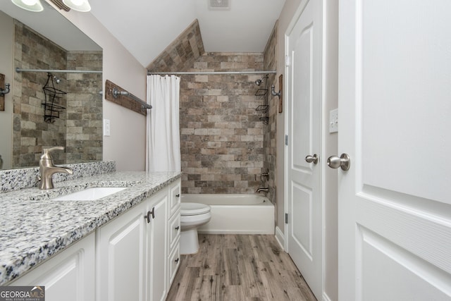 bathroom featuring vanity, vaulted ceiling, shower / bath combo, toilet, and wood finished floors