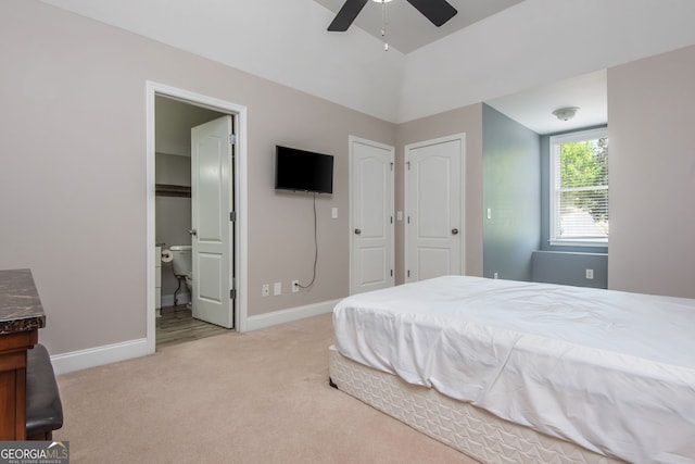 bedroom featuring baseboards, light carpet, ensuite bathroom, lofted ceiling, and ceiling fan