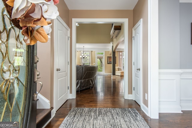 foyer featuring arched walkways, a notable chandelier, and dark wood-style floors