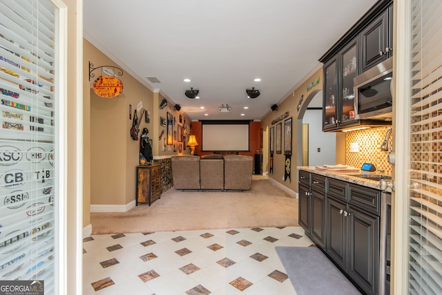 interior space featuring stainless steel microwave, arched walkways, baseboards, and ornamental molding