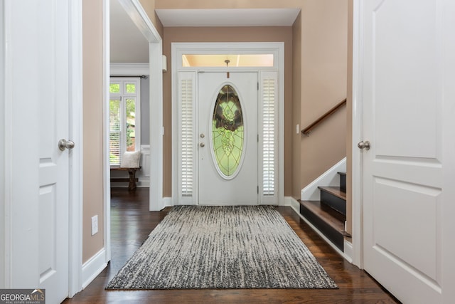 foyer with dark wood-type flooring, baseboards, and stairway