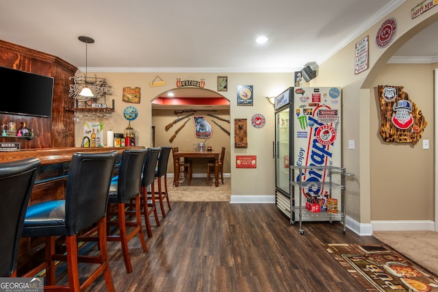 bar with arched walkways, freestanding refrigerator, bar area, dark wood finished floors, and crown molding