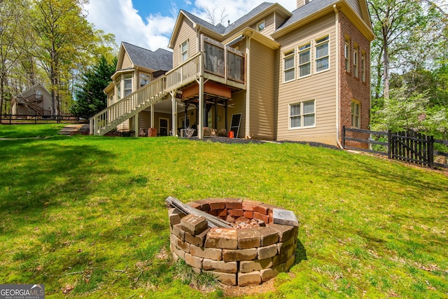 rear view of house with a lawn, stairs, fence, and an outdoor fire pit