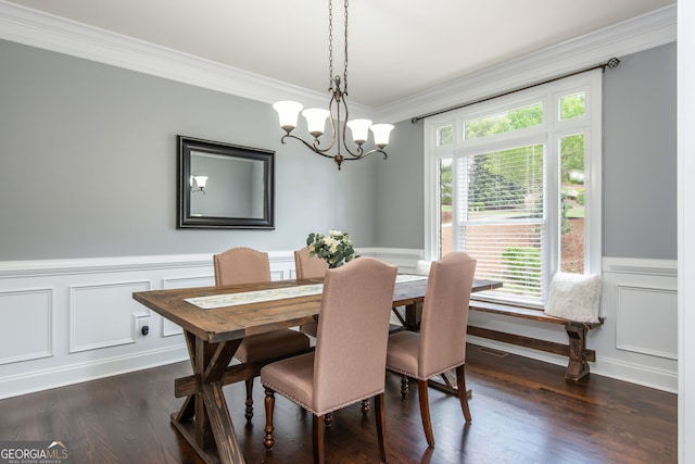 dining space featuring a notable chandelier, dark wood-style flooring, ornamental molding, wainscoting, and a decorative wall
