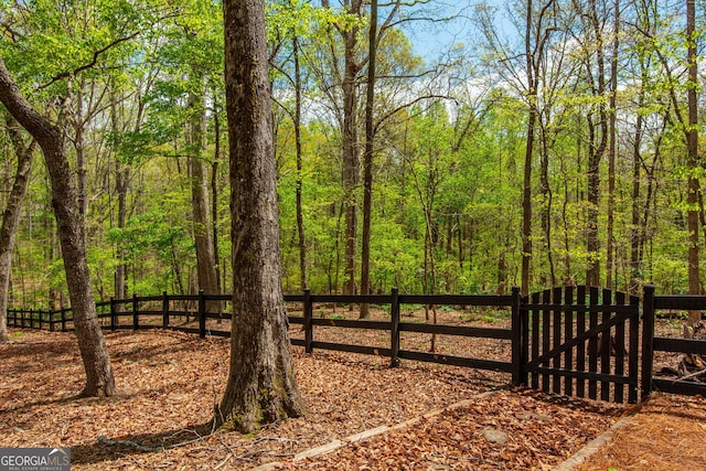 view of gate with a view of trees and fence