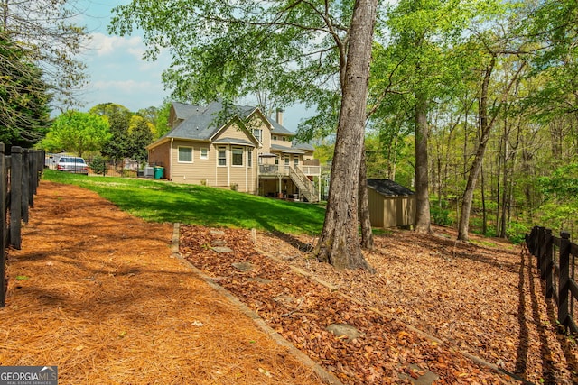 exterior space featuring an outdoor structure, stairway, a storage shed, a yard, and fence
